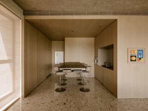 A modern kitchen with wood-paneled walls and a long table with stools.