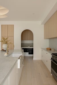 A minimalist kitchen with marble countertops and wooden cabinets.