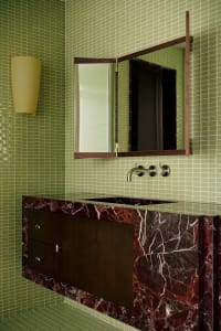 Bathroom interior featuring marble sink and green tiled walls.