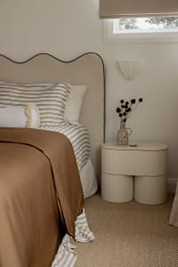 A modern minimalist bedroom with a comfortable bed and a unique nightstand.