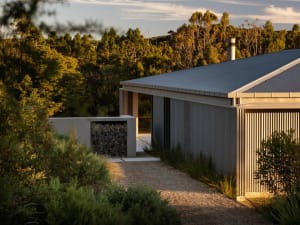 Modern residential exterior featuring corrugated metal siding and a gravel pathway.