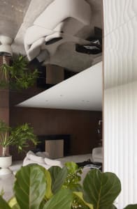 A minimalist living room with a natural wood floor, white furniture, and green plants.