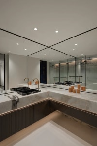 Modern bathroom with marble countertops, brass fixtures, and large mirrors.