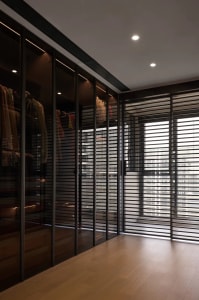 Modern closet with glass sliding doors containing clothes.