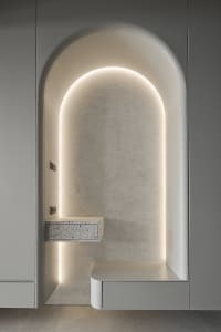 A minimalistic, modern design with an arched recessed alcove lined with terrazzo and lighted by concealed lighting.