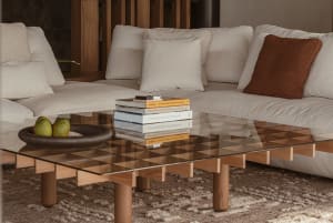 A modern living room featuring a glass coffee table and wood furniture.