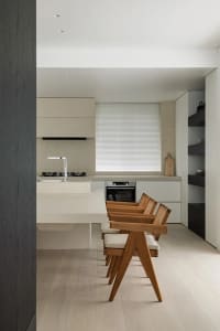 A modern minimalist kitchen with wooden elements and white countertops and appliances.