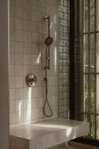 A modern bathroom with a tile shower featuring a handheld showerhead, overhead shower, and floating vanity.