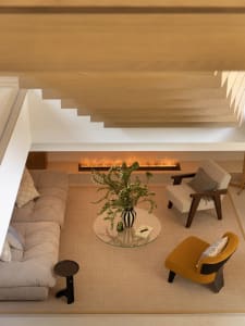 A modern living room with a fireplace, comfortable seating, and a central round coffee table with a vase and natural elements