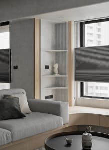 Modern minimalist living room featuring gray fabrics, concrete walls, wooden accents, and metal elements.