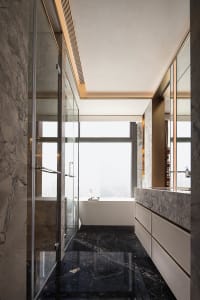 Modern bathroom with marble walls and floor, large windows, and a freestanding bathtub.