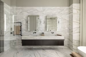 Modern bathroom featuring marble tiles, a floating vanity, and a large mirror.
