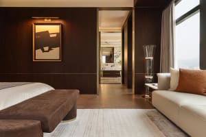 A modern bedroom suite featuring wooden walls, leather furniture, and marble accents.