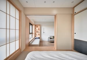 A minimalist bedroom featuring wood furnishings, fabric bedding, and plaster walls.