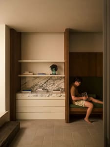 A reading nook with a modern marble and concrete design, featuring a person sitting and reading.