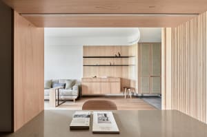 A minimalist living room featuring wood furniture and shelves.