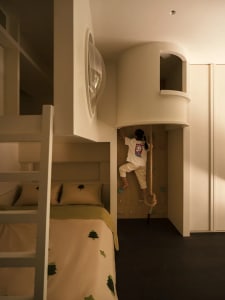 A child climbs on a rock wall in a modern playroom with light-colored materials.