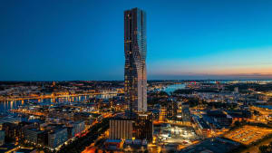 Modern skyscraper with glass and steel structure against a blue sky at dusk.