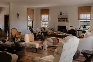 A modern living room with comfortable seating arrangements, wood flooring, and wicker decor.