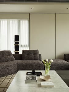 A modern living room with a large sectional sofa and a coffee table with a vase of tulips and books.