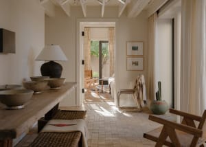 A modern living room with wooden furniture, white walls, and large windows.