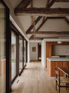 A modern minimalist kitchen with hardwood floors and concrete elements.