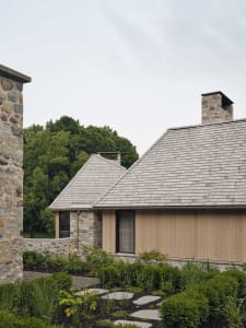 A modern residential exterior featuring wood and stone elements.