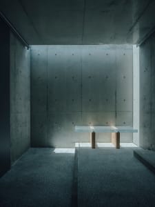 Minimalist interior design featuring concrete walls and a glass table.