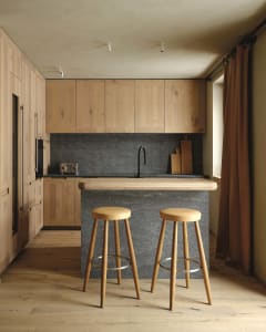 Modern kitchen with stone countertop and wooden stools.