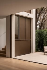 Modern home entryway with black metallic door and tiled flooring, featuring a minimalist design style.