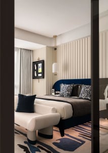 A modern bedroom featuring a fabric upholstered bed and geometric patterned rug.