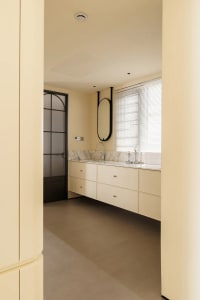 Modern minimalist bathroom with white marble cabinetry and flooring, featuring a sleek floating vanity and a large oval mirro