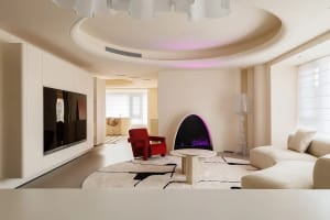 Modern living room featuring a neutral color palette, contemporary furniture, and a fireplace with purple lighting.