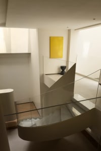 A modern minimalist staircase with transparent glass railings and steps, featuring minimalist design elements and a bright ye