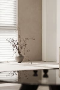 A minimalist interior space with concrete elements and a vase of dried flowers.