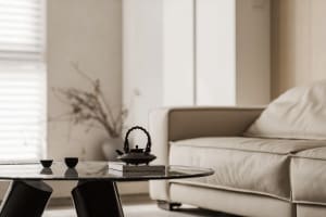 Minimalist living room featuring a glass coffee table and a leather sofa.