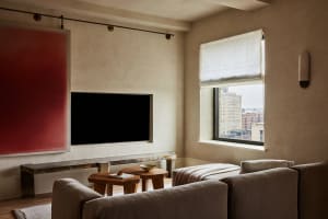 Modern minimalist living room featuring marble accents and textured fabric sofa, with a large window showcasing urban citysca