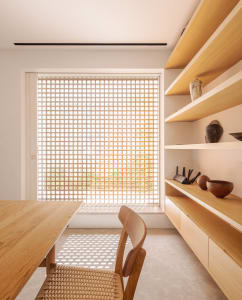 A modern minimalist home office featuring wooden furniture, featuring a table, chairs, and built-in shelves.