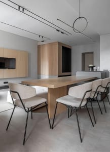 Modern residential kitchen featuring wooden dining table, fabric upholstered chairs, and metal accents.