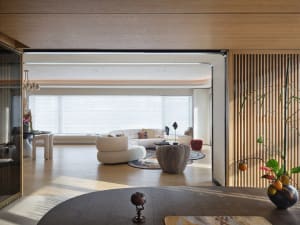 A modern, minimalist living room with wooden furniture and a large window.