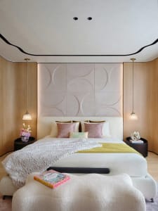 Modern bedroom with a bed adorned with pillows and blankets, featuring a wooden headboard and fabric textures.