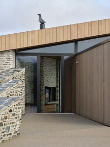 Facade of a minimalist architectural exterior featuring stone and wooden materials.