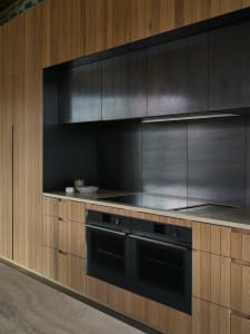 Modern minimalist kitchen with wooden cabinets and stainless steel appliances.