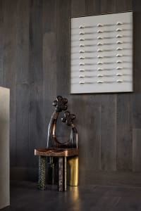 A modern artwork featuring metallic elements against a wooden wall background.