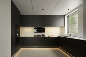 Minimalist kitchen with black cabinets, integrated appliances, and LED lighting beneath the cabinets and along the floor.