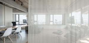 Modern office conference room with concrete walls and floor, large windows, and minimalist furniture.