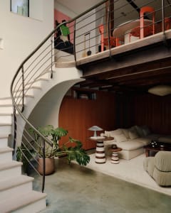 Modern living space featuring concrete flooring, a curved staircase, and potted plants.