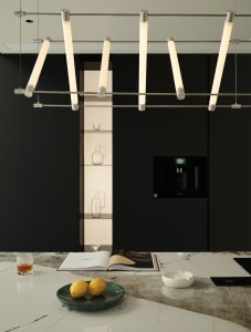 Modern minimalist residential kitchen with marble countertops, featuring sleek black cabinets and contemporary lighting.