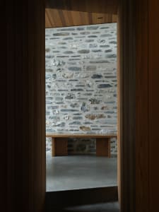 A minimalist interior with concrete walls and wooden furniture.