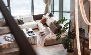 A minimalist living room with a white marble coffee table and a woman reading a book on a beige sofa.